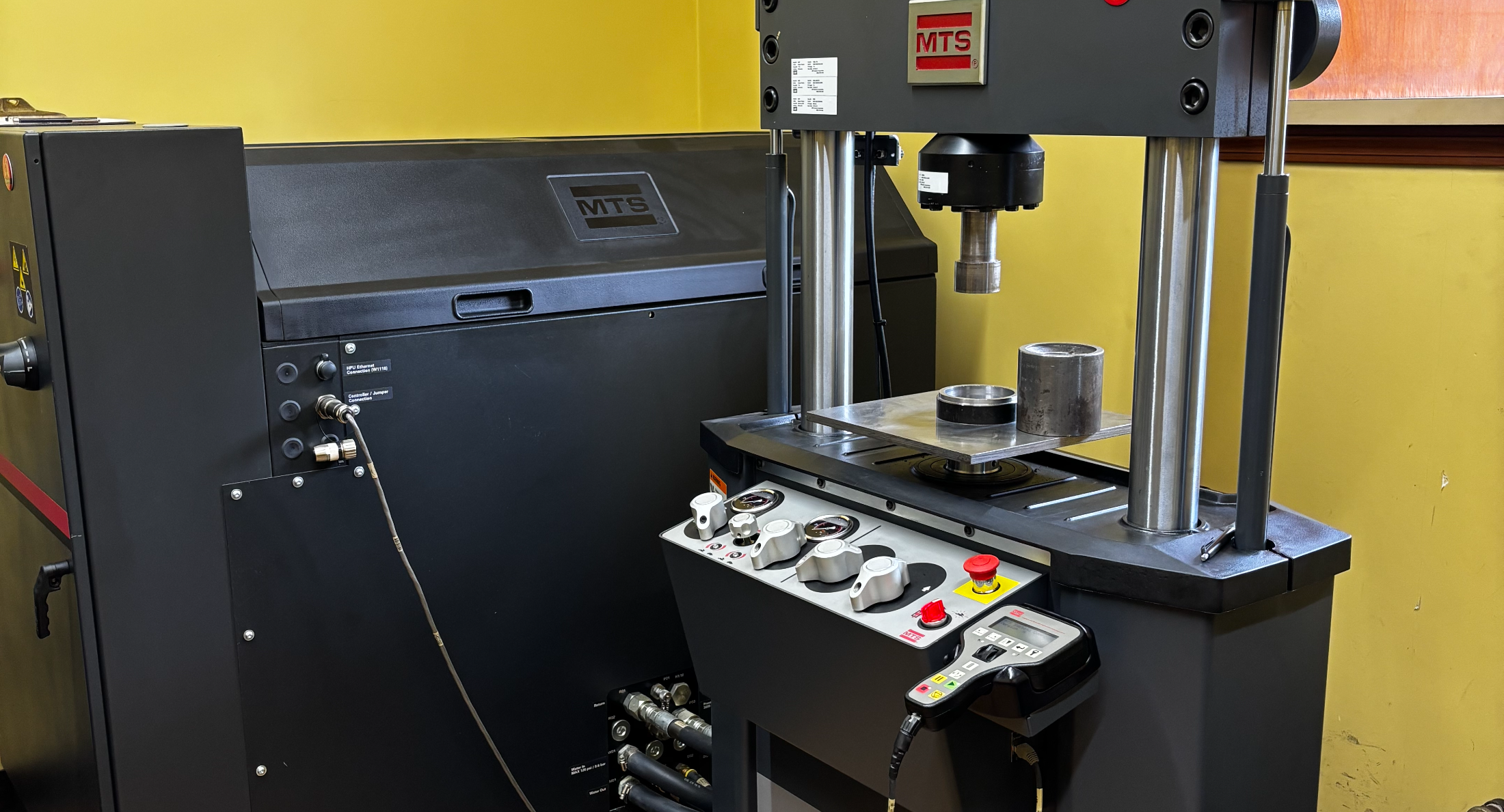 MTS servo-hydraulic test frame with a rubber specimen loaded, in the Corry Rubber accredited laboratory